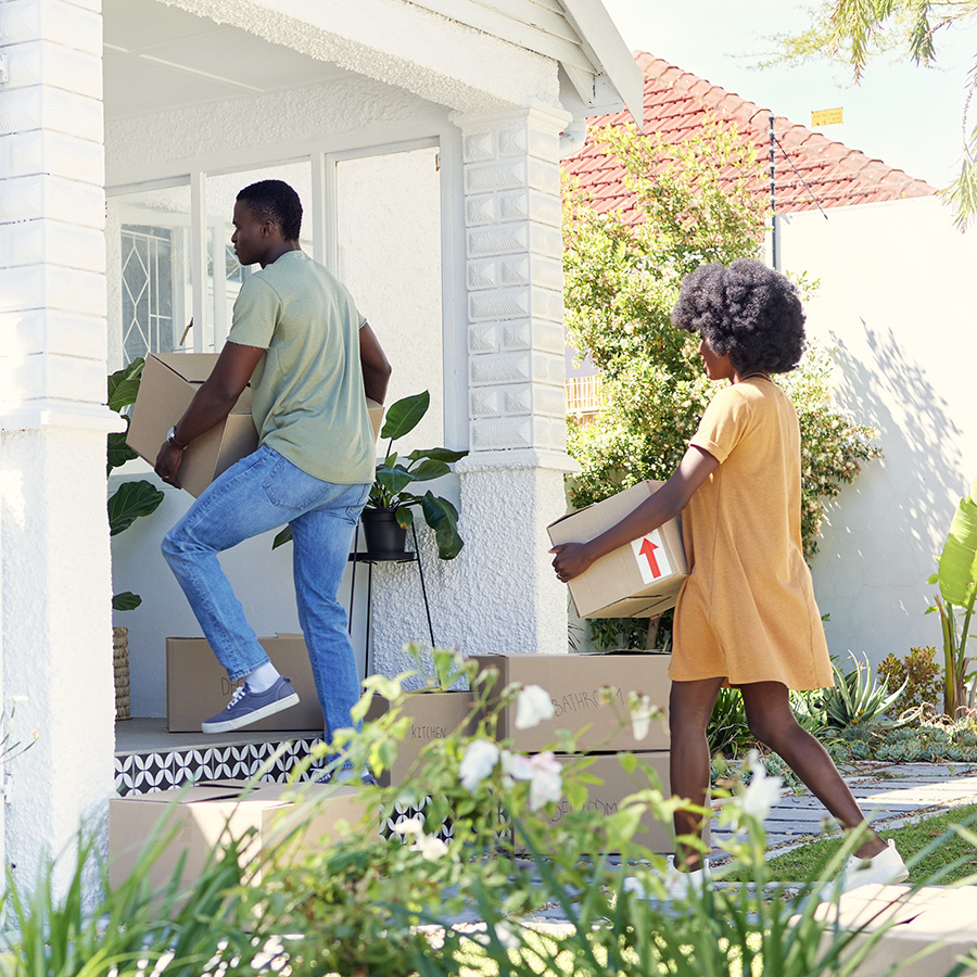 couple carrying boxes into their new house on moving day
