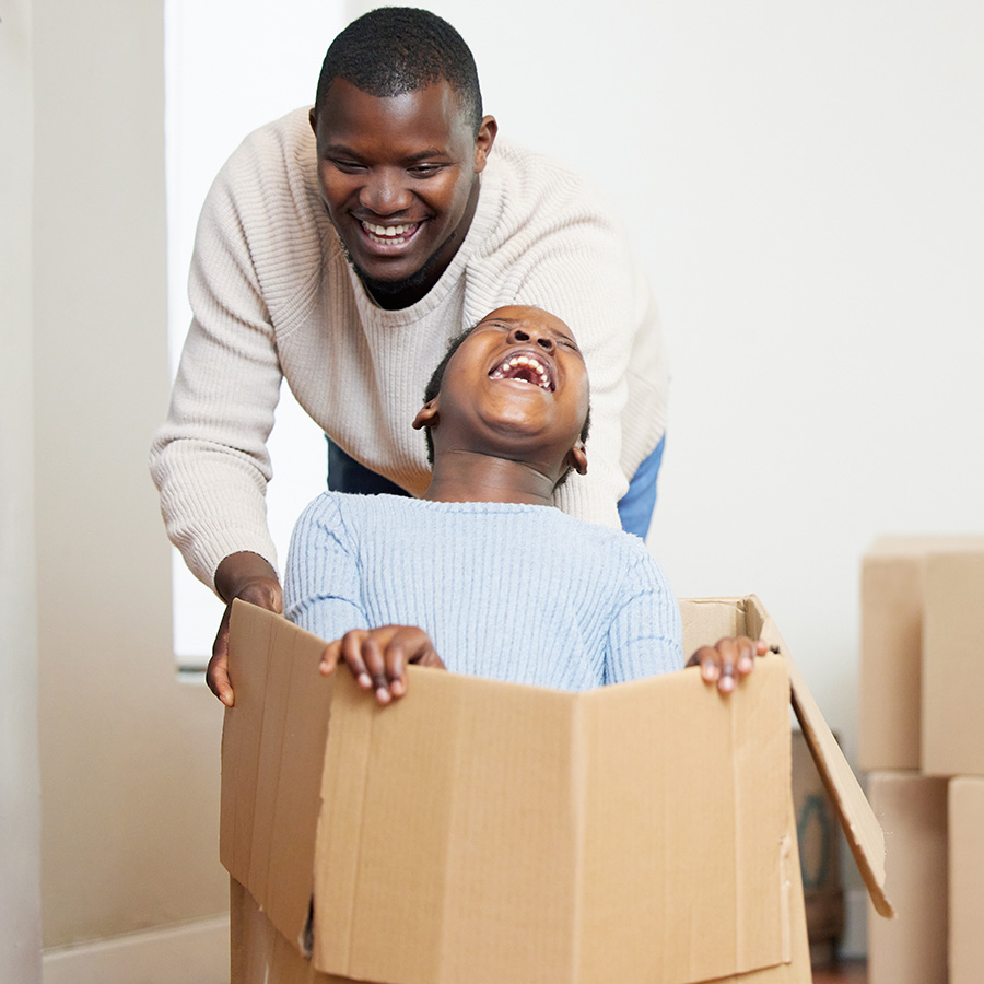 father and son enjoying a fun moment with a box on moving day