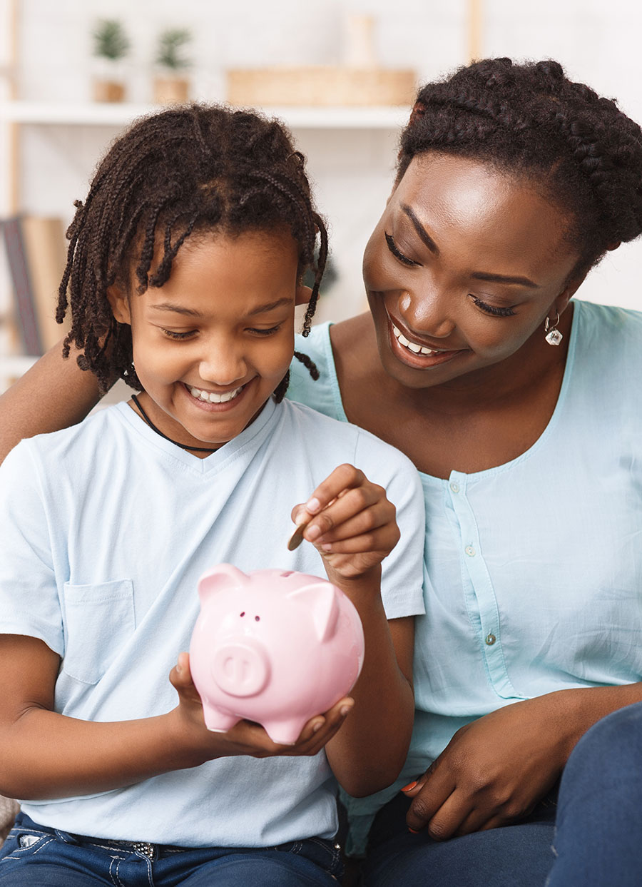 young girl putting money in a bank with an older relative